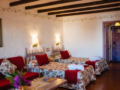 Chambre d'hôtel confortable avec deux lits simples, poutres en bois et motifs floraux décoratifs.