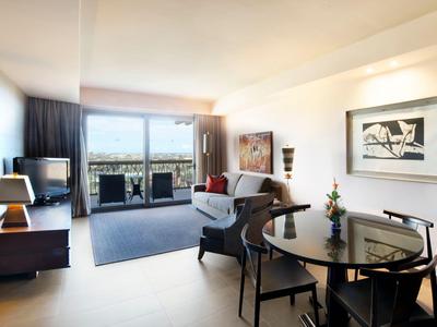 Helle, moderne Hotelzimmer mit offenem Wohnbereich und Balkon mit Blick ins Freie.