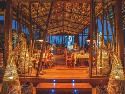 Acogedora cabaña de madera con luz cálida y linternas decorativas en un entorno tropical.