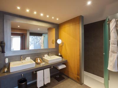 Bagno moderno con due lavandini, grande specchio e doccia a filo con accappatoi.