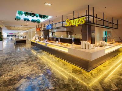 Modernes Buffet mit Suppenstation in einem hellen Gastraum mit Marmorfußboden.