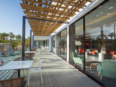 Moderne buitenruimte van hotel met terrasmeubilair en glazen gevel