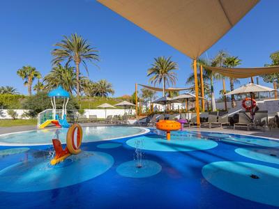 Kleurrijke waterspeelzone met glijbanen en palmbomen onder een heldere hemel in een tropisch resort