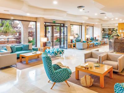 Lichte hotellobby met moderne zitgedeeltes en grote ramen met uitzicht op tuin