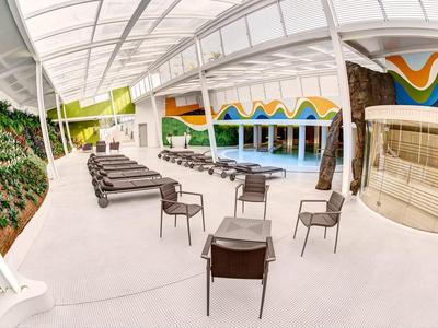 Modern outdoor pool area with lounge chairs, chairs, and colorful wall design.