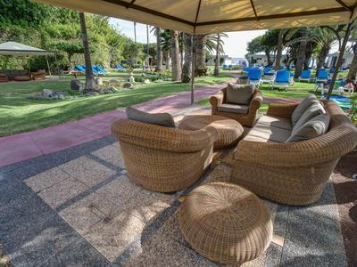 Cozy rattan seating area under a canopy in a hotel's garden.
