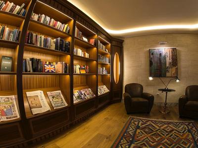 Cozy reading area with bookshelves, armchairs, and rug in a hotel.
