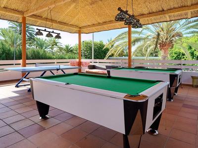 Terraza cubierta con mesa de billar y ping pong con vista al paisaje verde.