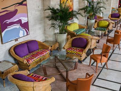 Cozy seating area with wicker chairs and colorful cushions in a modern lounge setting.