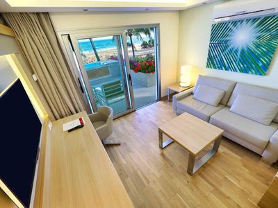 Living room with beige sofa, wooden coffee table, desk, and balcony with ocean view.