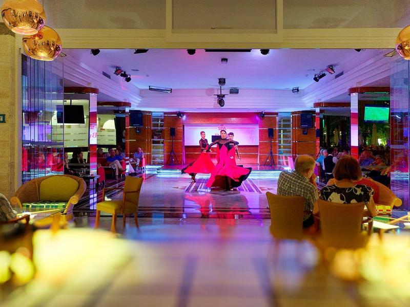 Interior of a colorful bowling alley with people sitting and watching a player bowling.