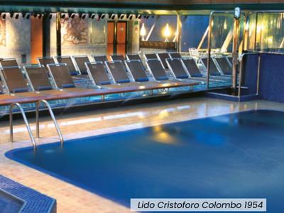 Piscina cubierta con azulejos azules y tumbonas en un hotel.