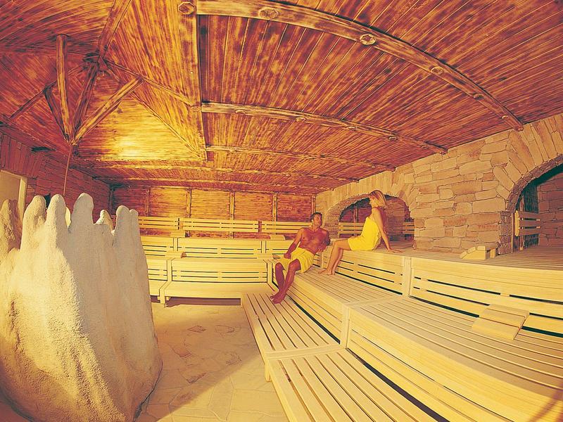 Salle de sauna confortable avec bancs en bois, murs en pierre et lumière chaude