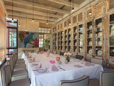 Elegante sala de comedor con mesa larga, manteles blancos y sillas modernas con luz cálida.
