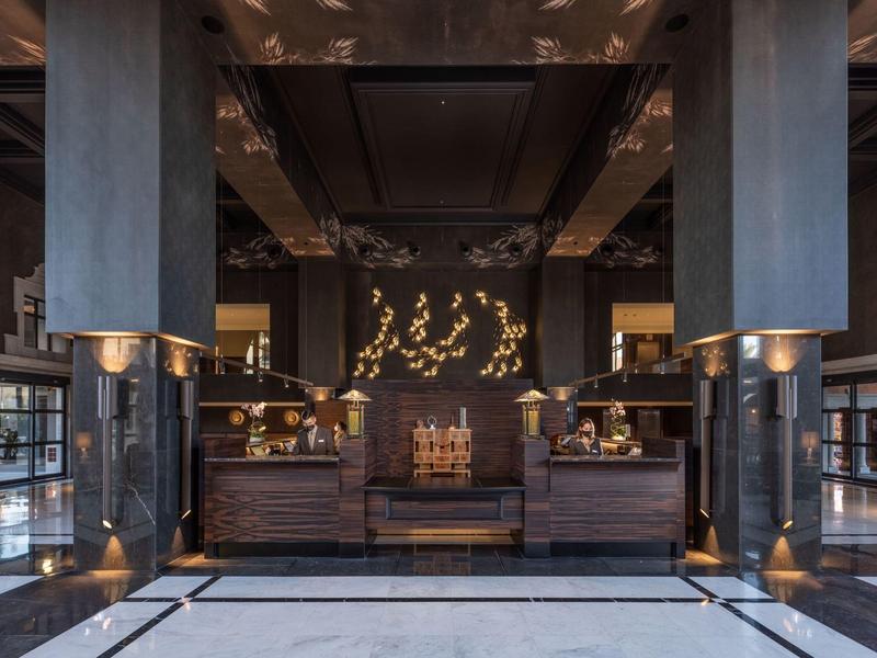 Elegante vestíbulo de hotel con madera oscura, esculturas y luces cálidas.