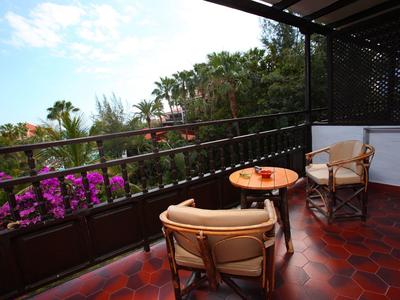 Balcony with two chairs, small table, and view of lush tropical plants.