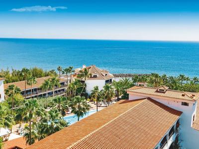 Luxuriöses Hotel mit Pool und Meerblick unter blauem Himmel.