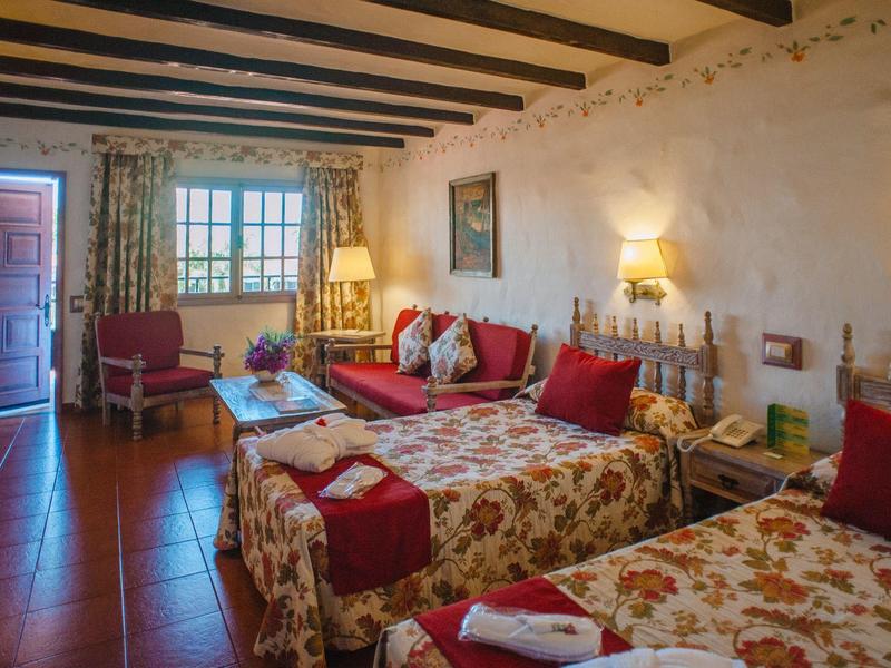 Cozy hotel room with two beds, red accents, and rustic decor.