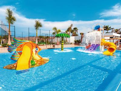 Piscina colorata con scivoli d'acqua e palme in un resort soleggiato.