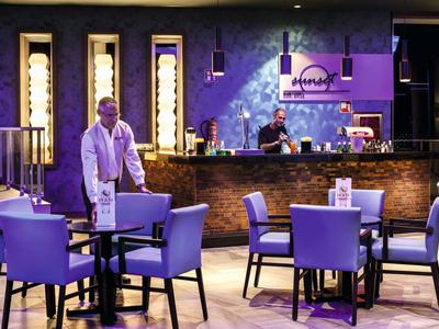 Modern hotel restaurant with purple lighting and stylish seating areas.