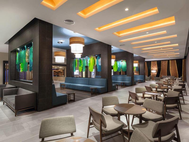 Ristorante di hotel moderno con aree salotto eleganti e illuminazione accentuata sul soffitto.