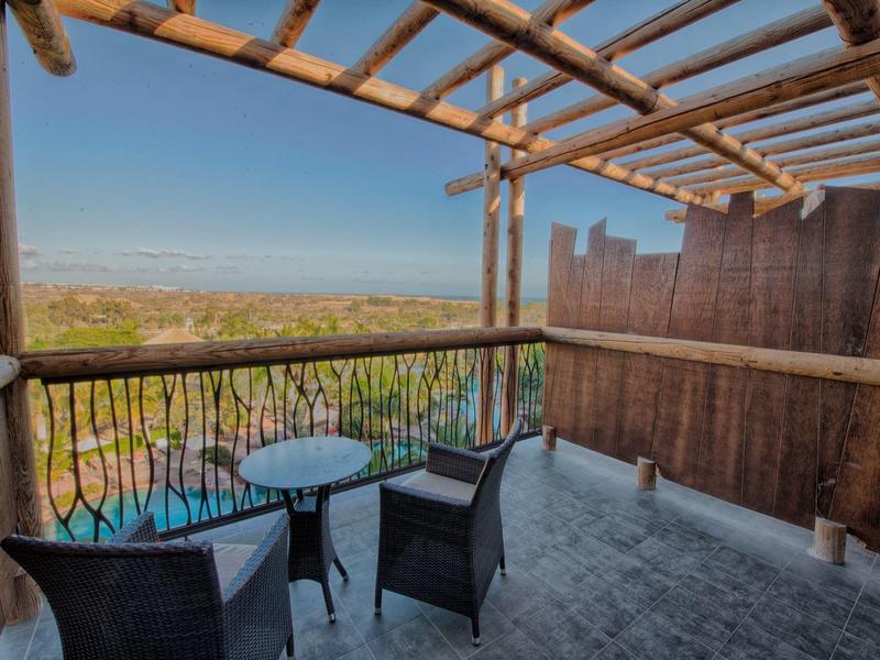 Balcone con sedie, tavolo, vista su paesaggio e cielo sereno, struttura in legno.
