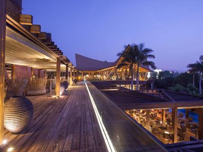 Wooden deck with warm lighting and modern structures under a twilight sky at a tropical resort.