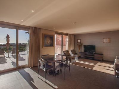 Bright hotel suite with dining table, seating area, and balcony with outdoor view.