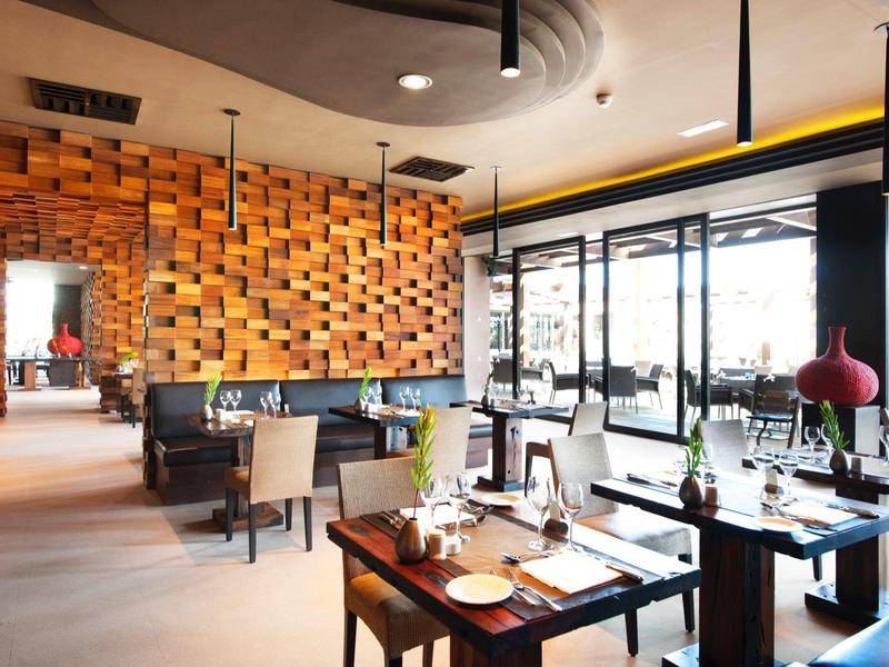 Modern hotel restaurant with wooden décor, large windows, and neatly set dining tables.