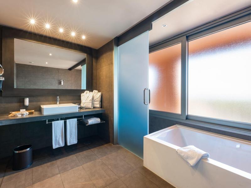 Modern hotel bathroom with large bathtub, double sinks, and spacious vanity area.