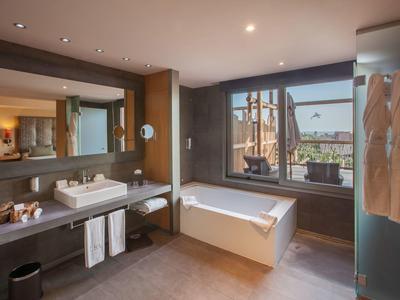 Bagno moderno con vasca, doppi lavandini e grande finestra aperta su terrazza.