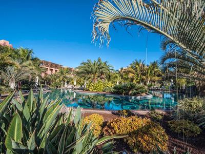 Piscine d'hôtel entourée de plantes tropicales sous un ciel bleu