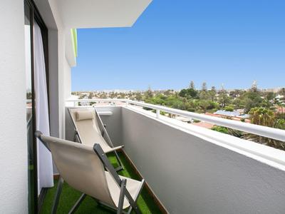 Balcony with chairs overlooking a suburban area under a clear blue sky.
