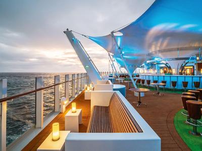 Modern bench and lighting on the outdoor deck of a cruise ship overlooking the sea at sunset.