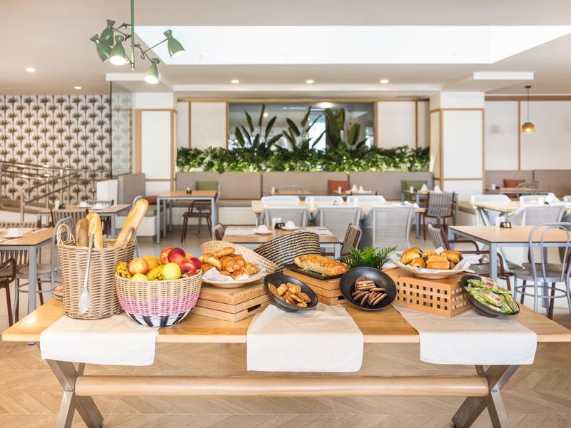 Hotel dining area with a table full of fresh bread, fruits, and breakfast items served buffet-style.
