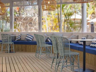 Cozy patio dining with wicker chairs and blue cushioned bench seating under hanging lamps.