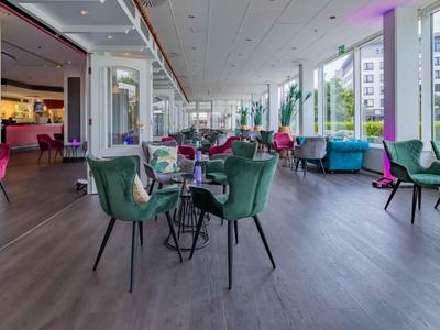 Helle, moderne Hotellounge mit bunten Sesseln und großen Fenstern mit Stadtausblick.