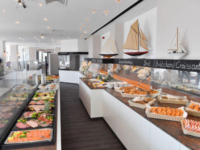 Buffet mit verschiedenen Speisen in einem modernen Restaurant mit Segelboot-Dekor an der Wand