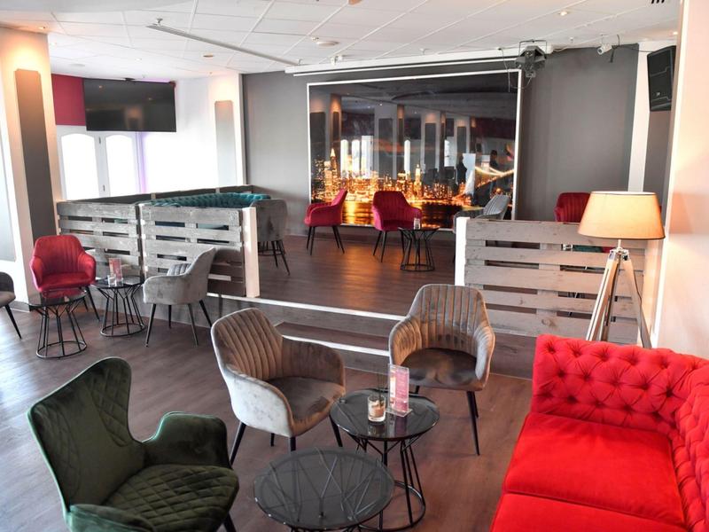 Modern eingerichteter Hotel-Lounge-Bereich mit Sesseln, Sofa und Tischchen.