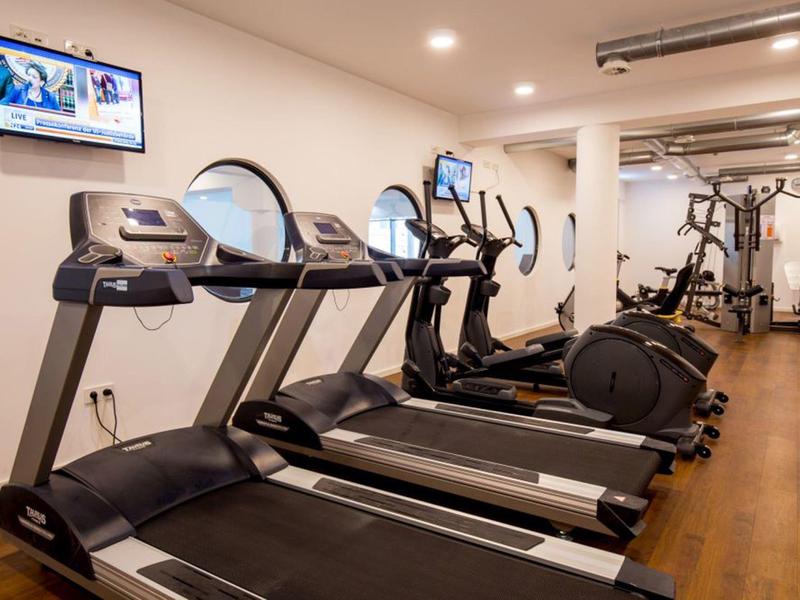 Moderner Fitnessraum mit Laufbändern, Crosstrainern und Kraftgeräten in einem Hotel.