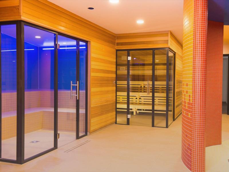 Moderner Wellnessbereich mit Sauna und Dampfbad, warm beleuchtet und einladend.