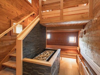 Intérieur en bois chaleureux avec escalier et coin salon dans un chalet de montagne.