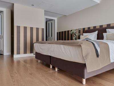 Modernes Hotelzimmer mit Doppelbett, Holzboden und gestreifter Wandgestaltung.