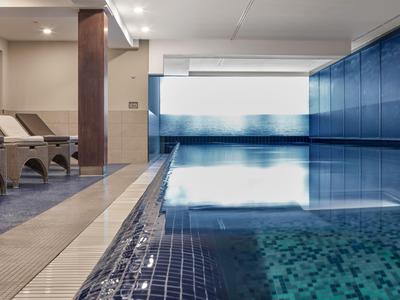 Modernes Hallenbad mit Liegestühlen und großen Fenstern für Tageslicht.