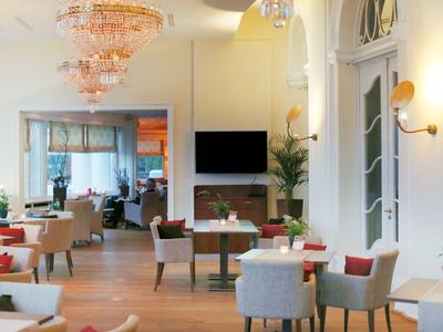 Eleganter Hotel-Loungebereich mit gemütlichen Stühlen, Holzboden und Kronleuchtern.