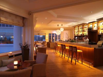 Gemütliche Hotelbar mit Lederstühlen, warmem Licht und Blick auf die Stadt bei Dämmerung.