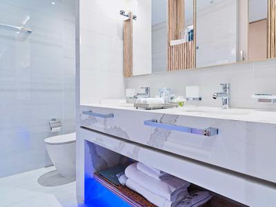 Modernes Badezimmer mit weißem Waschbecken, Spiegel und Handtüchern unter der Arbeitsplatte.