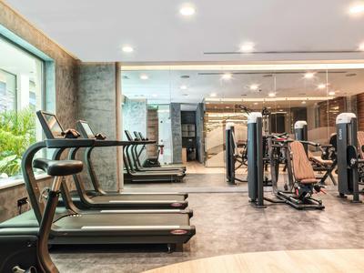 Modern gym with treadmills and strength equipment next to large windows.