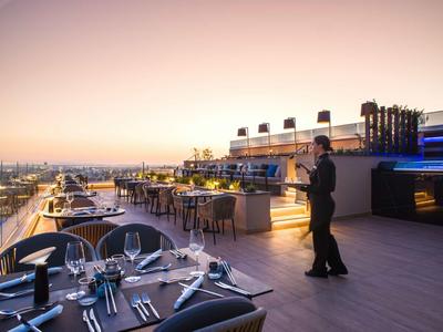 Rooftop terrace with set tables and city view at sunset
