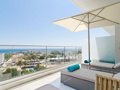 Terrassenblick aufs Meer mit moderner Lounge, weißem Sonnenschirm und klarem Himmel.